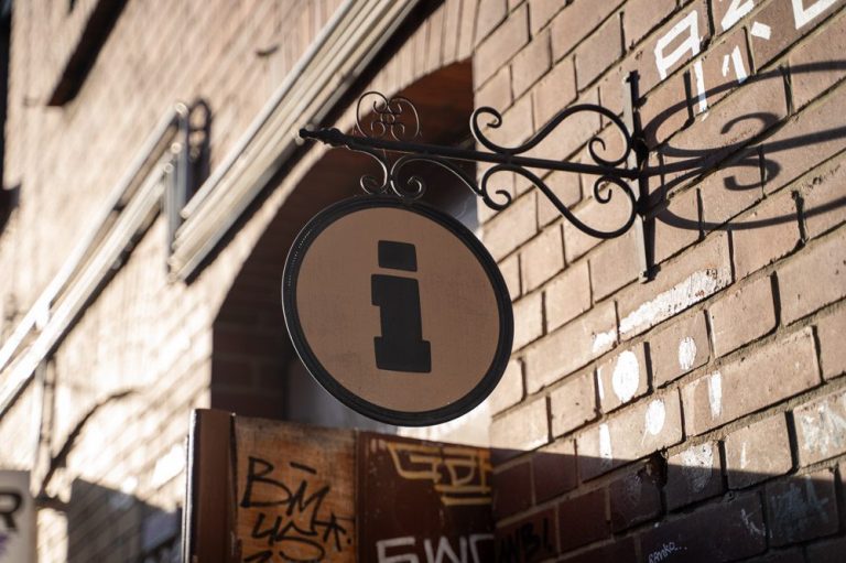 Intensität Rundes Informationsschild an Ziegelfassade mit schwarzem Symbol.